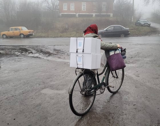 122022_Woman Bicycle Boxes_©GGC_Bilyi Kolodiaz Pizza Party + Food Boxes and Blankets Distribution_Ukraine Response