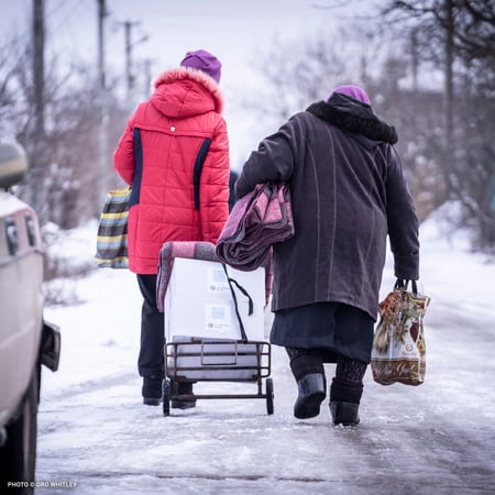 20230217_Two Women Walking Away with Boxes and Blankets_©Oro Whitley_Ukraine Response_Food Boxes and Blankets Distribution (Halystynove)-square