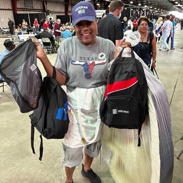 20230428_Phoenix_Stand_Down_Event_Person_Holding_Good_Packs_and_Dog_Bed_Smiling_©_GGC_Good_Packs-gallery-02