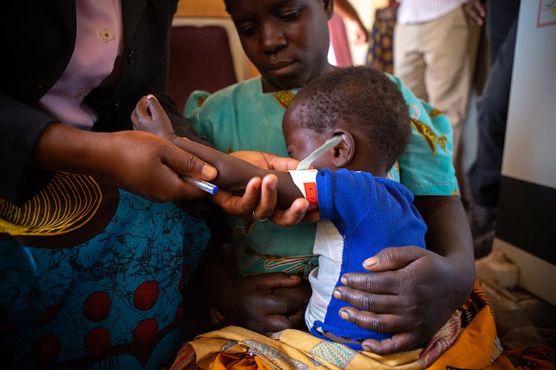 alt="child fighting starvation pictured with mother and doctor"