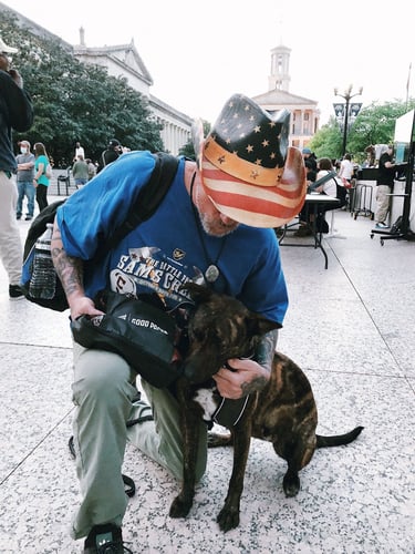 Man in American Flag Hat with Dog and Pet Pack at Good Packs distribution event in Nashville