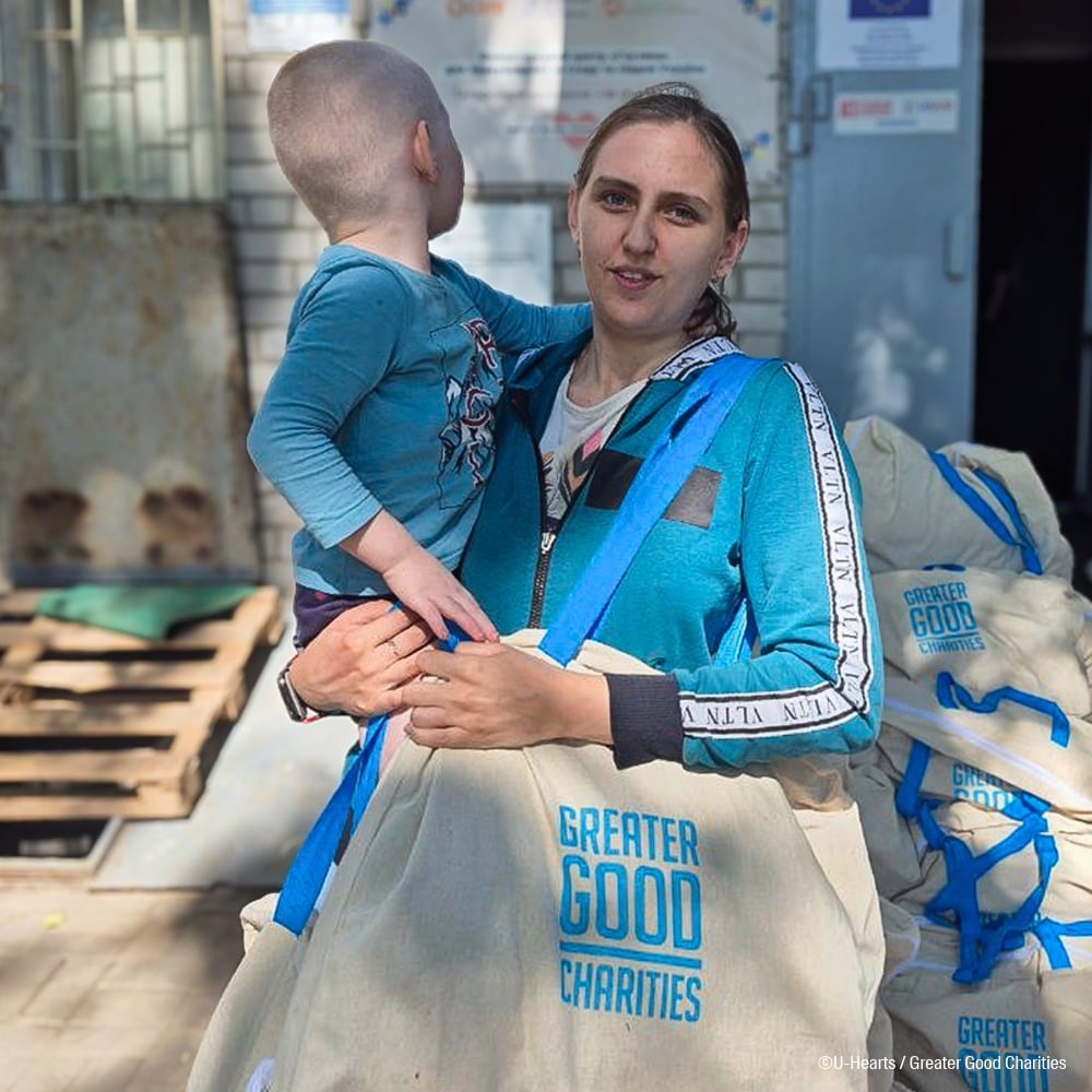 Ukrainian and child holding Greater Good Charities emergency pack Ukrainian and child holding Greater Good Charities emergency pack